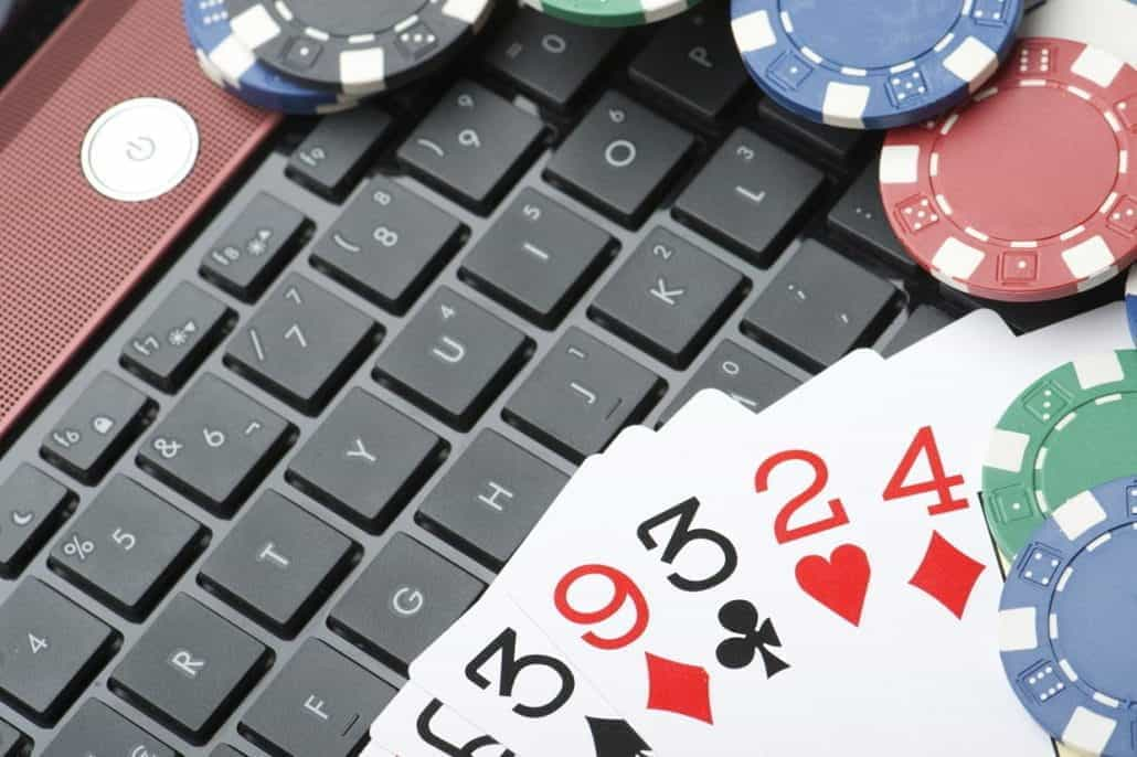 A pile of cards and poker chips stacked on a laptop's keyboard.