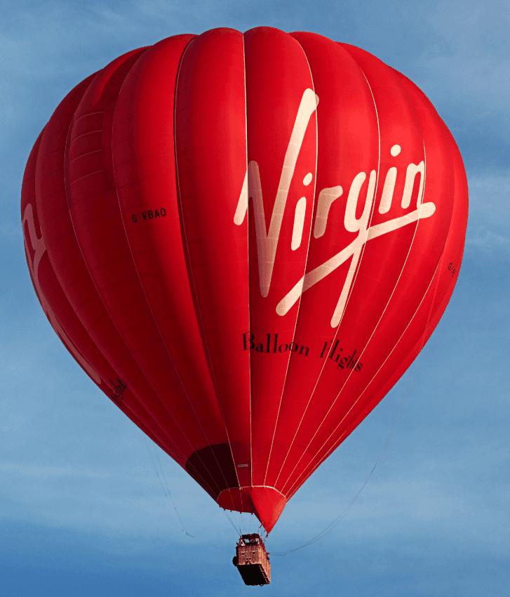 A Virgin red hot air balloon in a bright blue sky.