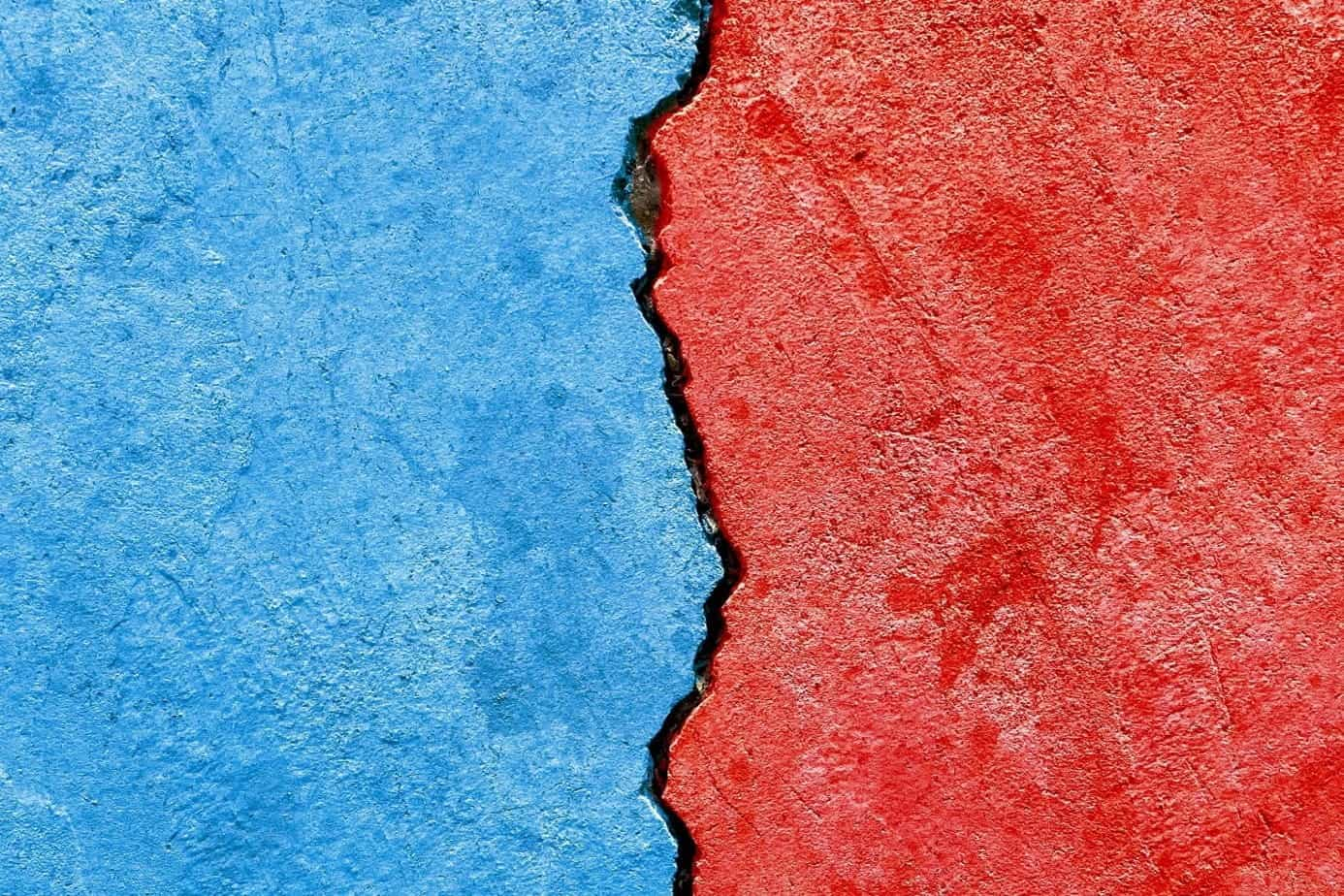 A wall part red, part blue, with a crack along the center dividing the colors.