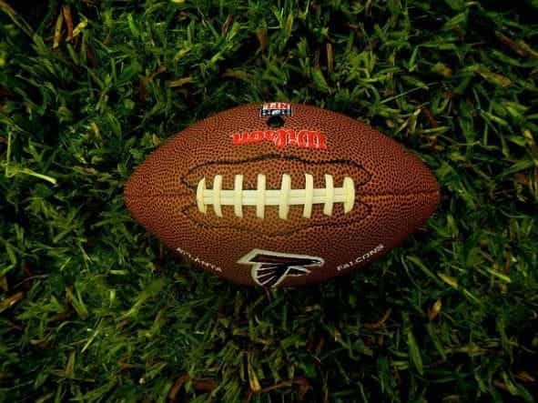 An American football laying flat on a grassy pitch.