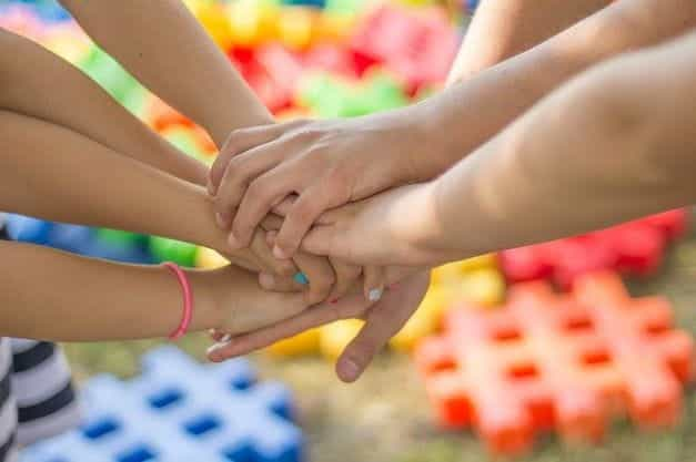 Seven children’s hands coming together in unison.