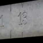 The number 13 is engraved in a concrete, while other numbers around it are blurred.