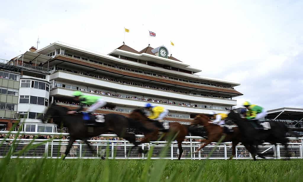 Horses thunder past a packed Newbury Grandstand.?