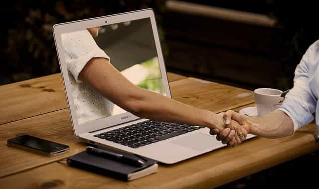 A person’s arm extending out of a laptop screen.