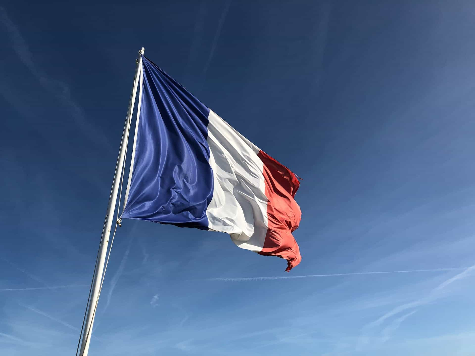 The French flag flying against a blue sky.