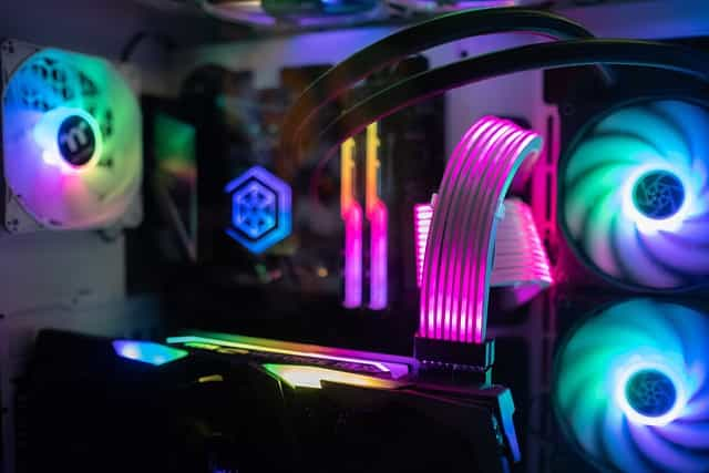 The inside of a high-end gaming computer, featuring several multicolored fans, the computer’s processor, graphics card, and other hardware.