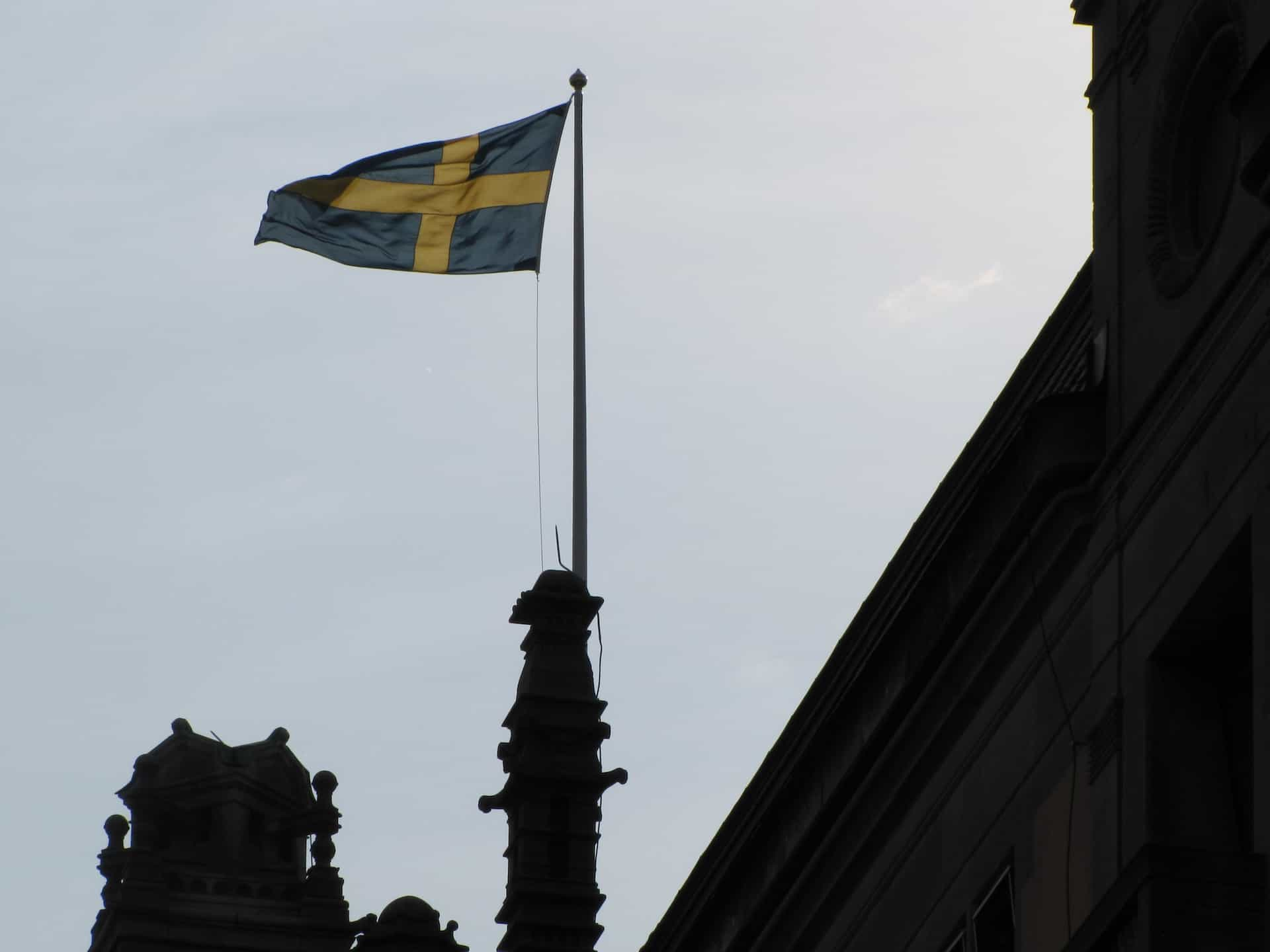 A flag hoisted at the top of a building against a blue sky.